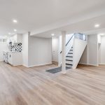 A modern and bright basement with new flooring, painted walls, and lighting
