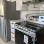 After image of a newly renovated kitchen with brand new stainless steel appliances, and new tiling and cabinets
