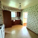 Before image of a dated kitchen with old wallpaper