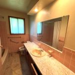 Before image of an old washroom with dim lighting and dated finishes